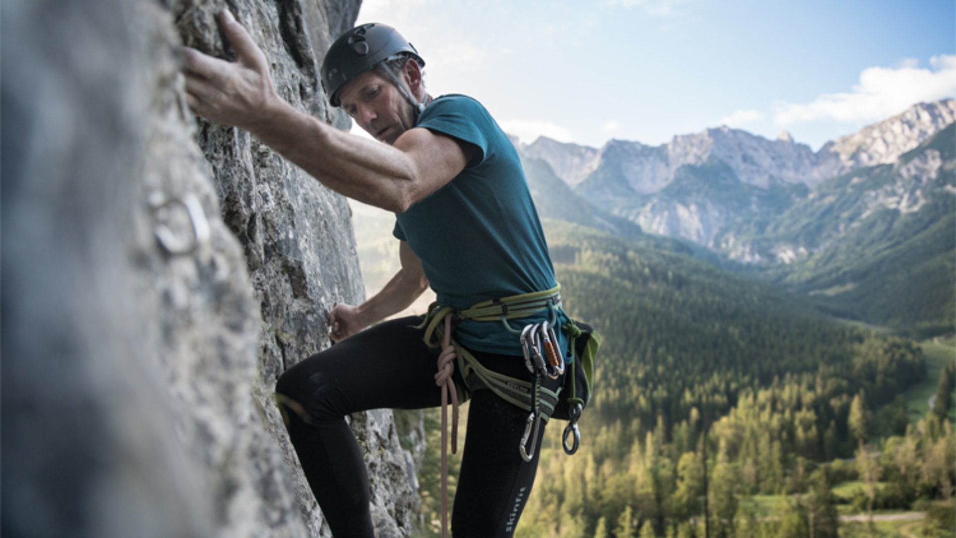 Climbing in Pyhrn-Priel | Photo: Oberösterreich Tourismus GmbH / Robert Maybach A man climbing a vertical rock face and looking at the mountains in the background.