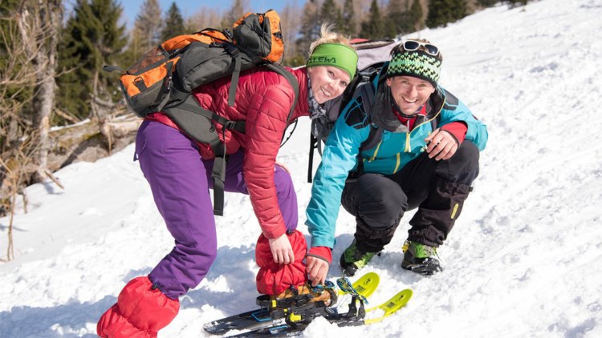 Schneeschuhwandern mit Abenteuer Management | Foto: www.LARESSER.com Ein Mann und eine Frau bücken sich um sich die Schneeschuhe anzuziehen.